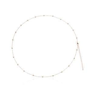 Detailed close-up of a gold waist chain featuring delicate metal beads and a lobster clasp