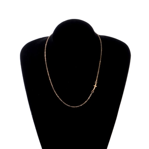 Détail d'un collier minimaliste doré avec pendentif croix sur un buste en velours noir