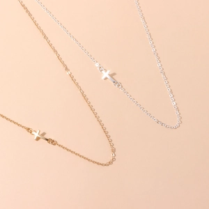 Gros plan de colliers avec pendentif croix minimaliste en or et argent et chaîne fine