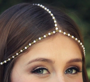 Close-up detail of golden chain headpiece with white pearls and Y-shape tassel design