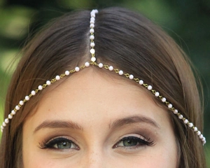 Close-up of bohemian gold chain forehead headband with elegant white pearls on a model