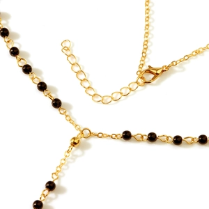 Detail of gold chain necklace featuring black beads and adjustable lobster clasp closure