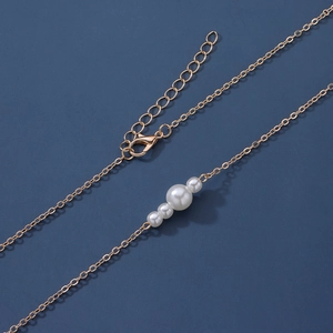 Détail macro de la chaîne de taille dorée ornée de perles blanches et fermoir mousqueton