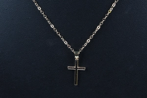 Vista macro de un colgante de cruz chapado en oro pulido en un collar minimalista