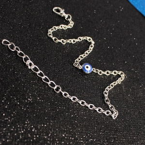 Detailed view of silver evil eye bracelet with lobster clasp on black glitter background