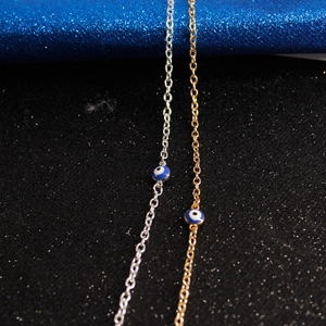 Macro shot of silver and gold evil eye bracelets with blue enamel charm detail