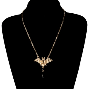 Detail van een gouden vleermuis hanger met een zwarte kraal op een display voor sieraden
