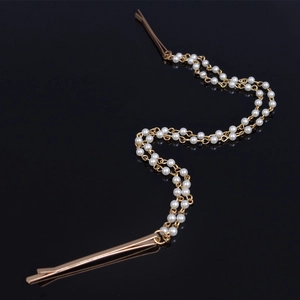 Detail of dual-layered pearl strand hair clips with gold-toned metal pins on black background