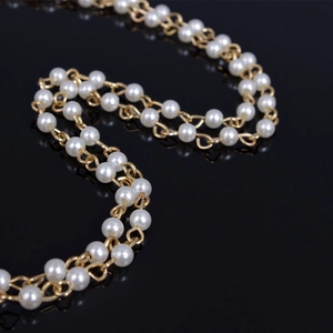 Detail view of a dual-layer gold-plated alloy necklace with elegant round white pearls