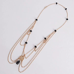 Detail of multi-layer gold chain with black beads and a star pendant with black gem