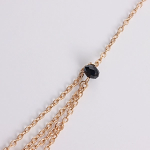 Close-up of golden multi-layer star head chain with a faceted black gemstone detail