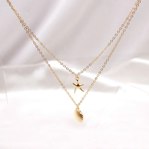 Detailed macro view of layered gold necklace with starfish and striped shell pendants