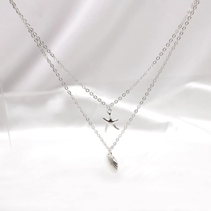 Macro detail of silver layered necklace with intricate starfish and seashell pendants