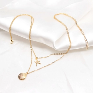 Detail of layered gold shell and starfish necklace on elegant white satin fabric