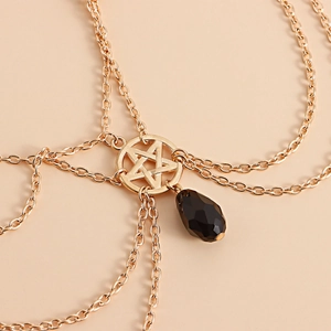 Detailed macro view of a gold multi-layer chain featuring a star ring and black crystal drop