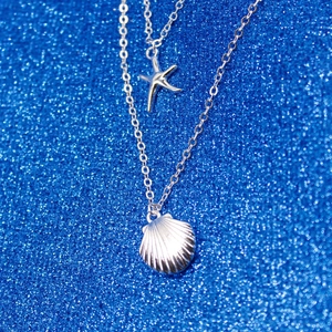 Close-up of silver multilayer necklace featuring starfish and seashell pendants