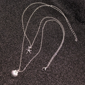 Multilayer silver necklace featuring starfish and seashell pendants on a dark background