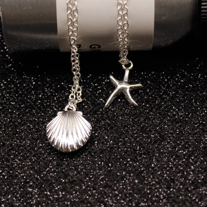 Detailed macro view of silver seashell and starfish pendants on a fine link chain