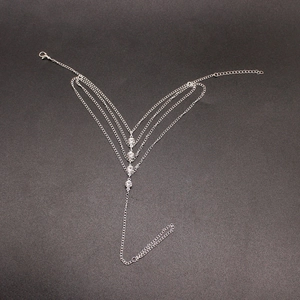 Détail d'une chaîne de cheville argentée multicouche avec strass et chaînes en forme de V