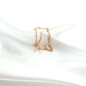 Nahaufnahme von goldenem Schleifenanhänger und feiner Kette auf elegantem weißem Satin