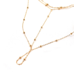 Détail d'une chevillère dorée multicouche avec de petites billes sur fond blanc pur