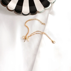 Detail eines feinen goldenen Schleifenarmbands mit verstellbarer Kette auf Seidenstoff