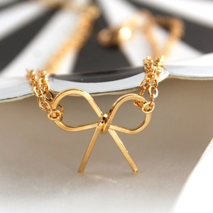 Nahaufnahme eines minimalistischen goldenen Schleifenanhängers mit feiner Halskette