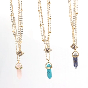 Detail of evil eye charms and hexagonal crystal stone pendants on gold bead chains