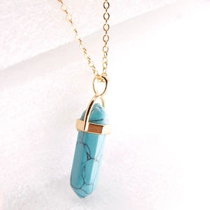 Detailed close-up of light blue hexagonal prism pendant on delicate gold chain necklace