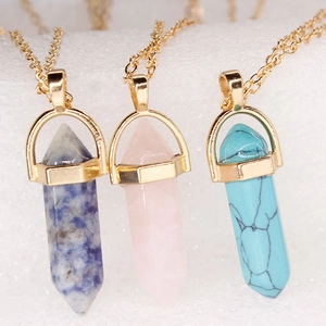 Macro view of triple-layered gold necklaces with lapis, rose quartz and turquoise pendants