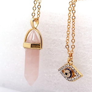 Macro detail of hexagonal pink crystal pillar and sparkling evil eye pendant necklace
