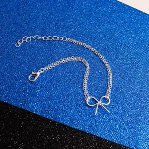 Detailaufnahme eines silbernen Schleifenarmbands mit Doppelkette auf glitzerndem Hintergrund