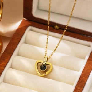 Macro view of gold heart projection necklace with zircon accents in wooden gift box