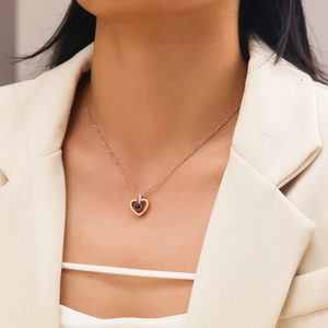 Detail of rose gold heart pendant necklace with black projection stone on a model