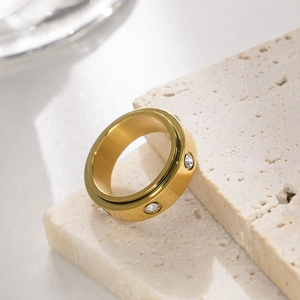 Close-up of a gold stainless steel spinner ring with inlaid zircons on stone decor