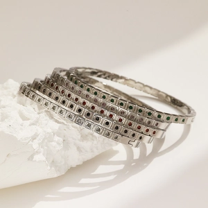 Dettaglio dei bracciali sovrapposti in acciaio inossidabile con zirconi quadrati colorati
