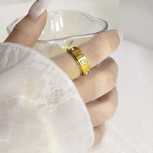 Detail of gold rotating ring with screw motifs and inlaid zircons on hand