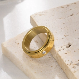 Detail of a rotating gold stainless steel ring with engraved hearts and a zircon stone