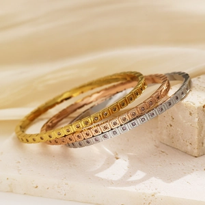 Vista macro di tre bracciali a griglia quadrata in oro, argento e oro rosa con cristalli