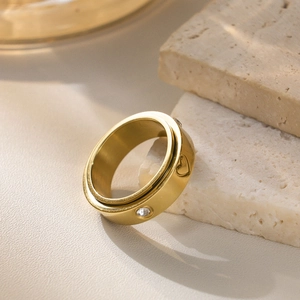 Detail of spinning gold heart ring with cubic zirconia on textured stone background