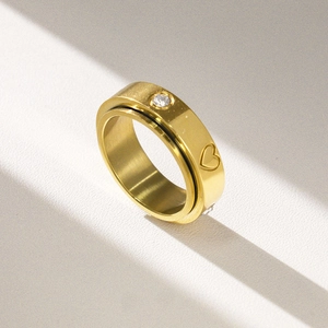 Detailed macro view of gold brushed stainless steel ring with heart engraving and zircon