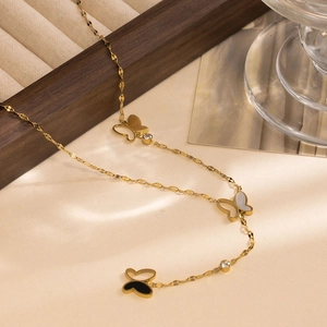 Elegant gold butterfly necklace with mother of pearl and crystal charms on a warm background