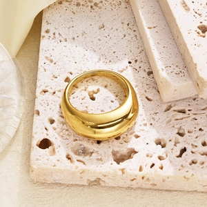 Polished gold thick dome ring displayed on natural stone with soft silk background