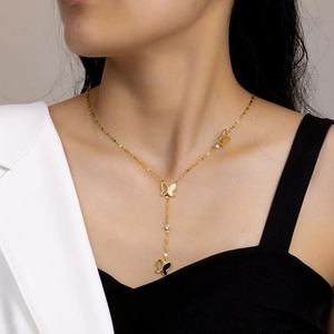 Elegant gold butterfly tassel necklace with black and white shell pendants on a model