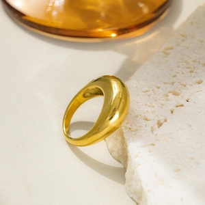 Close-up of golden minimalist ring with smooth mirror finish on white stone background