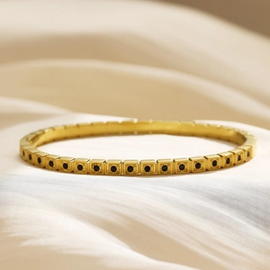 Dettaglio del bracciale in acciaio inossidabile dorato con maglie quadrate e zirconi neri