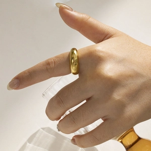 Close-up of a polished golden dome ring worn on finger, minimalist stainless steel jewelry