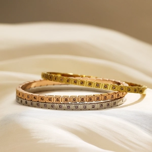 Dettaglio macro di braccialetti a rilievo in oro, oro rosa e argento con zirconi viola