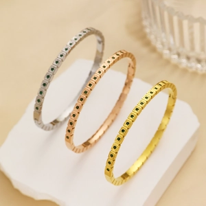 Dettaglio di tre bracciali sovrapponibili in acciaio inossidabile con pietre di zircone verde