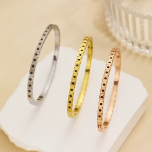 Dettaglio di bracciali a griglia quadrata in argento oro e oro rosa con pietre nere